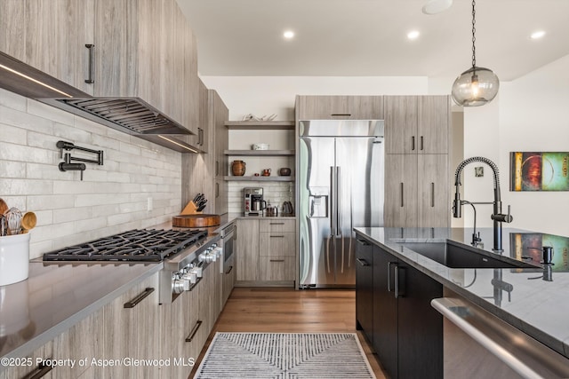 kitchen featuring tasteful backsplash, light stone countertops, appliances with stainless steel finishes, a sink, and modern cabinets