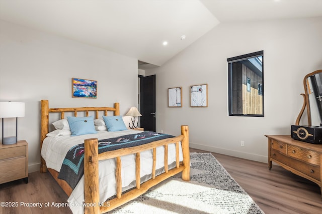 bedroom featuring lofted ceiling, baseboards, and wood finished floors