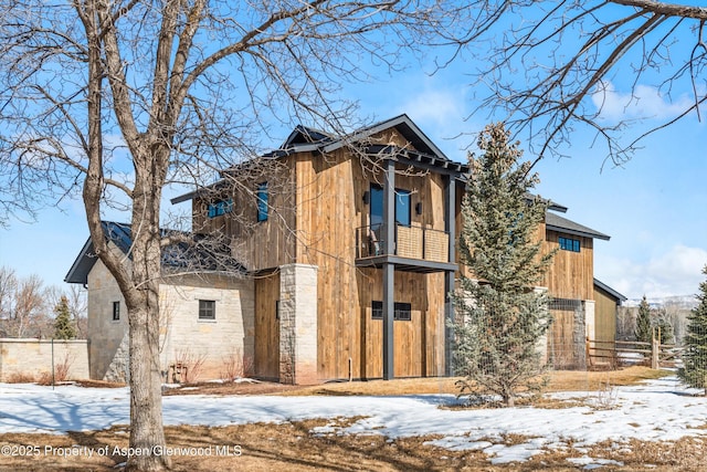 exterior space featuring stone siding, fence, and a balcony