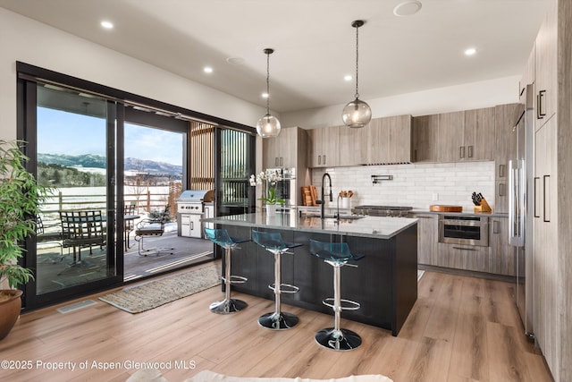 kitchen featuring light wood-style flooring, modern cabinets, a breakfast bar area, and a sink