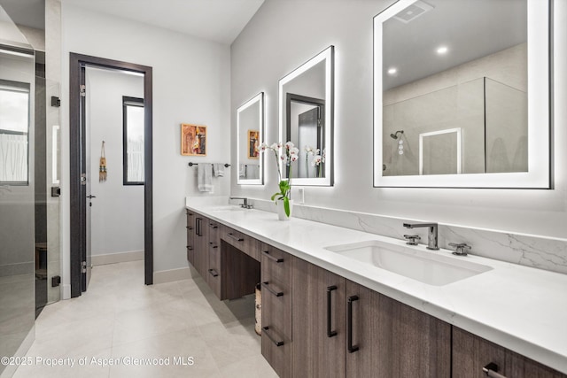 bathroom featuring double vanity, visible vents, a tile shower, and a sink