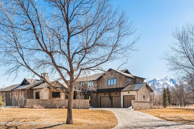 view of front of property featuring a front lawn, decorative driveway, a chimney, and an attached garage