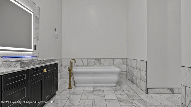 bathroom with vanity, a bath, and tile walls