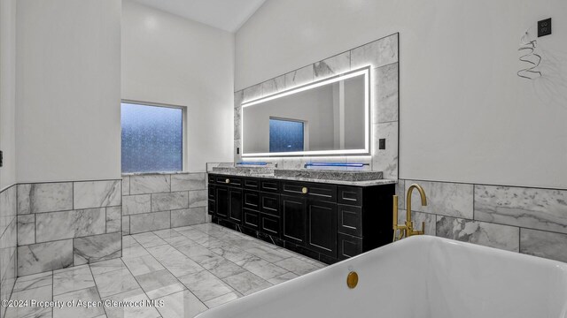 bathroom featuring a tub, vanity, and tile walls