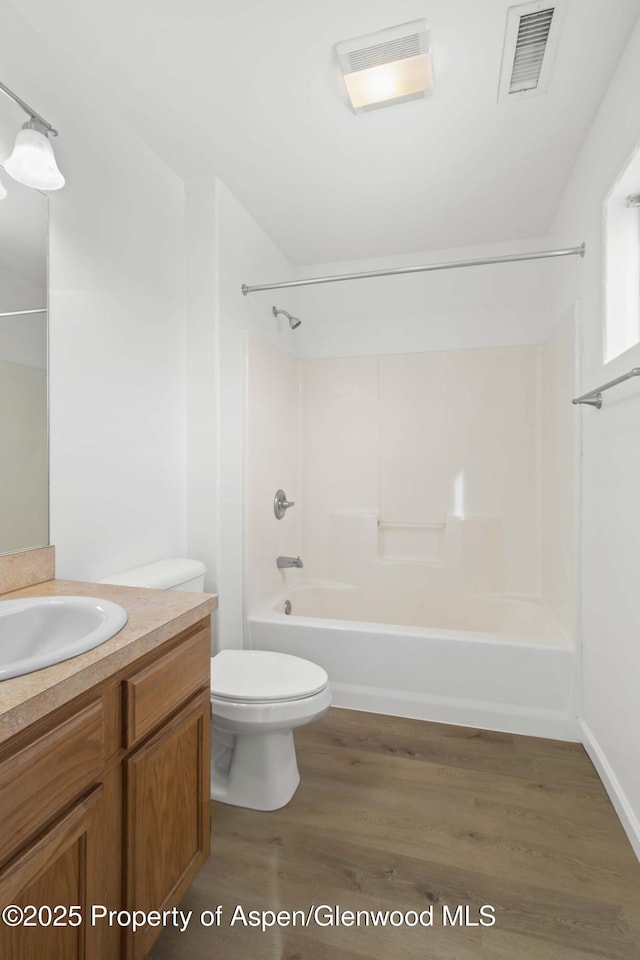 full bathroom with hardwood / wood-style flooring, washtub / shower combination, vanity, and toilet