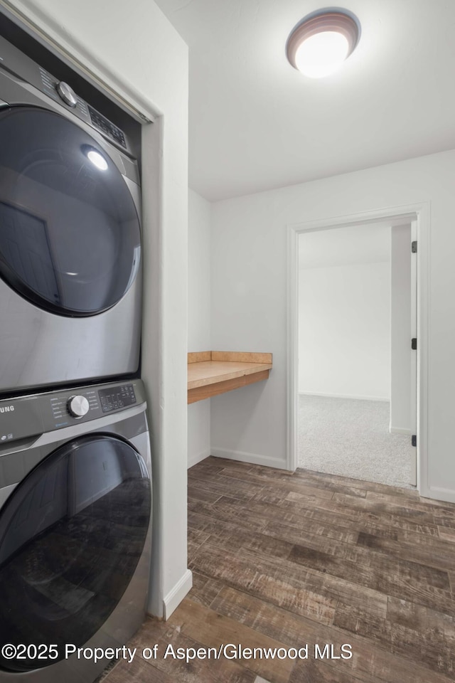 clothes washing area with dark hardwood / wood-style flooring and stacked washing maching and dryer