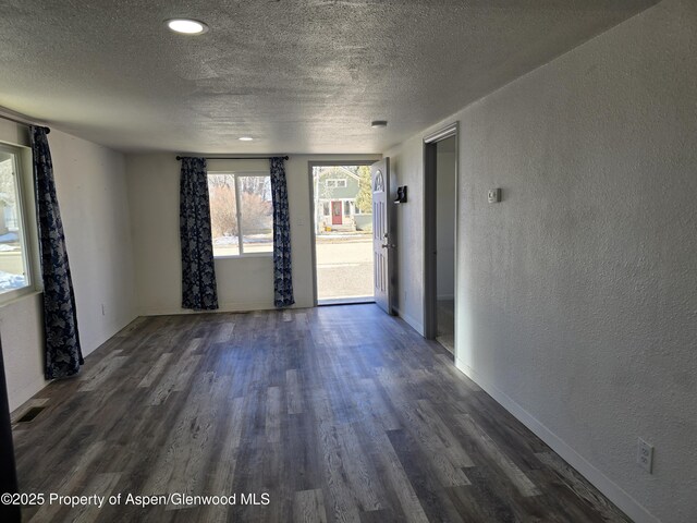 spare room featuring dark hardwood / wood-style flooring and a textured ceiling