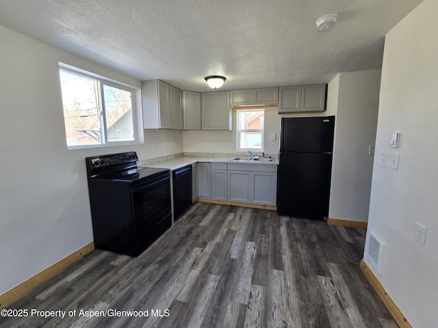 kitchen with gray cabinets, dark wood-type flooring, a textured ceiling, and black appliances