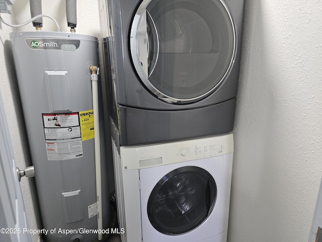 laundry room with water heater and stacked washer and dryer