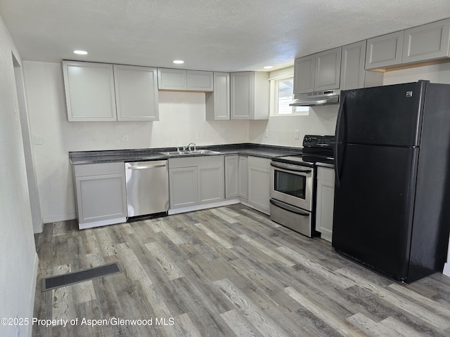 kitchen with sink, light hardwood / wood-style flooring, appliances with stainless steel finishes, gray cabinetry, and a textured ceiling