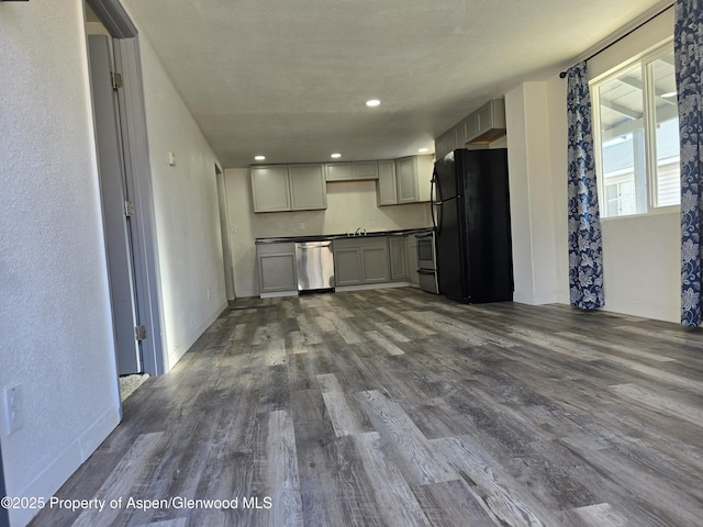 kitchen with sink, dark wood-type flooring, dishwasher, gray cabinetry, and black fridge