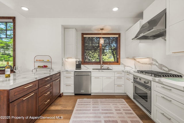 11 Pinon Ln, Carbondale, CO 81623 - kitchen with stainless steel appliances, wall chimney range hood, white cabinets, light stone countertops, and recessed lighting