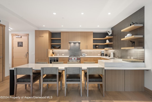 130 Wood Road 256 & 258, Snowmass Village, CO 81615 - kitchen with a kitchen breakfast bar, sink, high end stove, tasteful backsplash, and kitchen peninsula