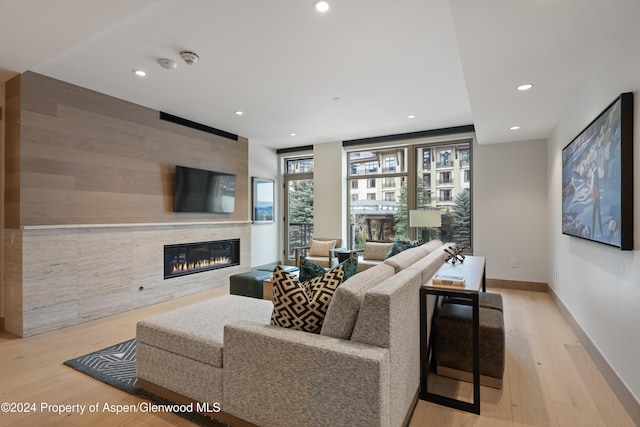 living room featuring a tiled fireplace and light wood-type flooring