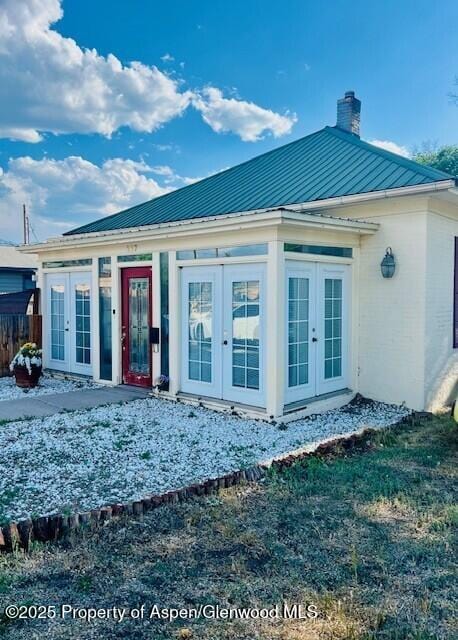 337 W Ave, Rifle, CO 81650 - view of front facade with french doors, a chimney, a metal roof, and a standing seam roof