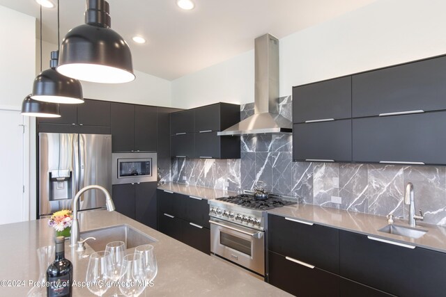 kitchen with sink, wall chimney range hood, stainless steel appliances, and hanging light fixtures