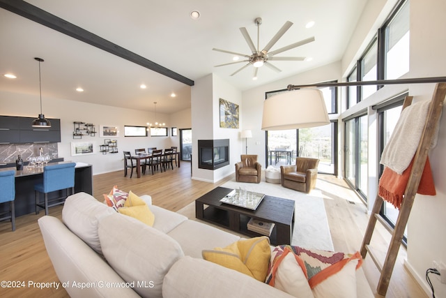 living room featuring ceiling fan with notable chandelier, a multi sided fireplace, light wood-type flooring, and lofted ceiling