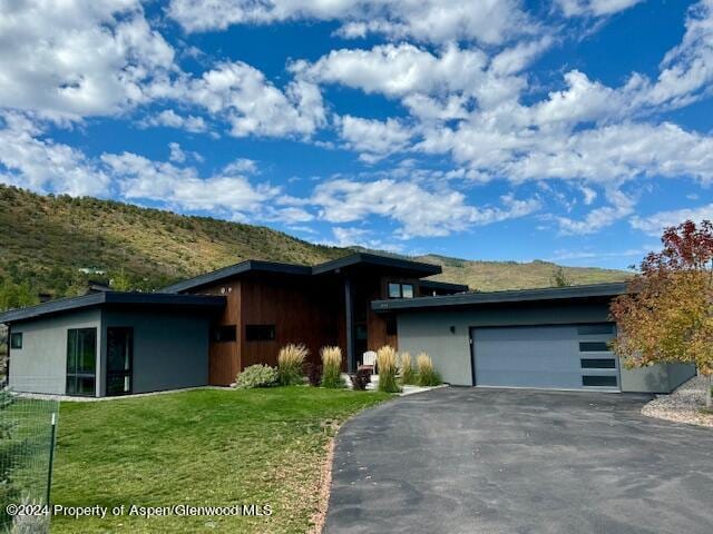 view of front of house with a mountain view, a garage, and a front lawn