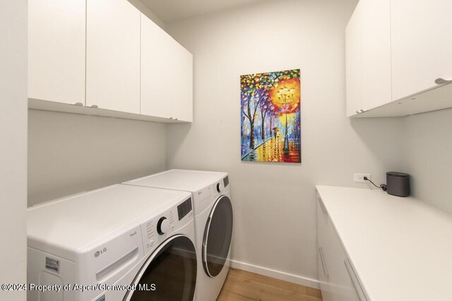 laundry room featuring cabinets, light hardwood / wood-style floors, and washer and dryer