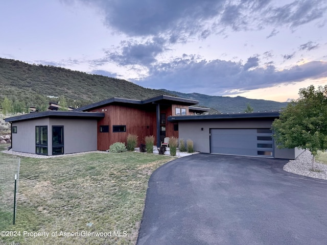 prairie-style house featuring a lawn, a mountain view, and a garage