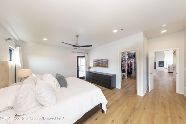 bedroom with a spacious closet, a closet, ceiling fan, and light hardwood / wood-style floors