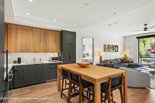 kitchen featuring ceiling fan, tasteful backsplash, sink, and light hardwood / wood-style flooring