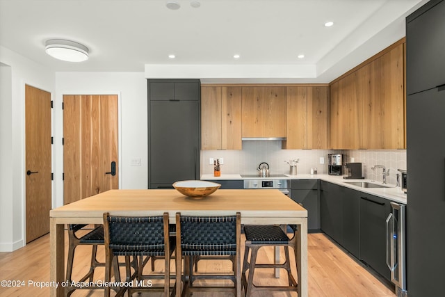 kitchen with a kitchen breakfast bar, light wood-type flooring, backsplash, and sink