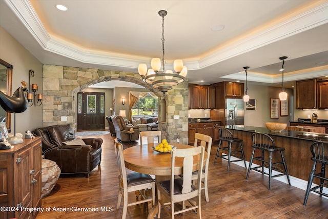 dining room with dark hardwood / wood-style floors, a raised ceiling, a notable chandelier, and crown molding