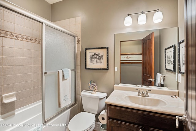 full bathroom featuring combined bath / shower with glass door, vanity, and toilet