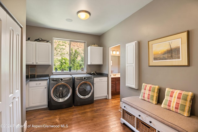 clothes washing area with separate washer and dryer, dark hardwood / wood-style flooring, cabinets, and sink