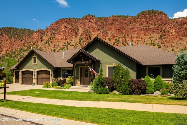 craftsman-style house featuring a mountain view, a front yard, and a garage