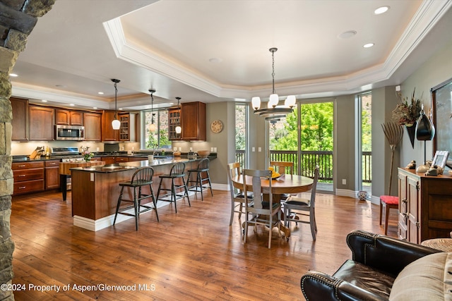 dining area featuring a raised ceiling, crown molding, dark hardwood / wood-style flooring, and a notable chandelier