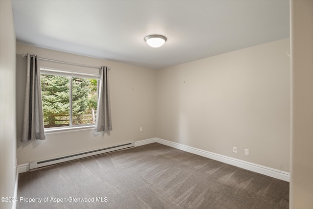 carpeted empty room with a baseboard heating unit