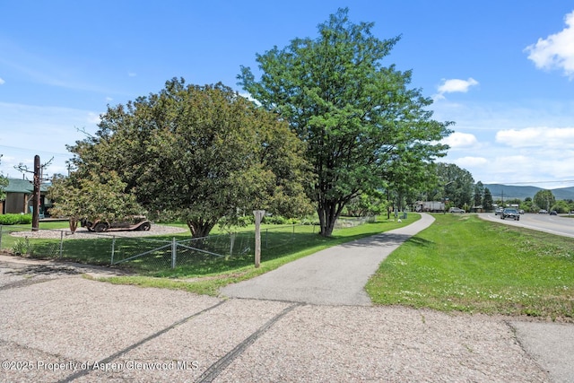 view of home's community with fence and a lawn