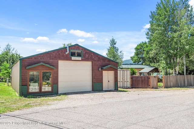 view of front of home featuring an outdoor structure, fence, and a garage