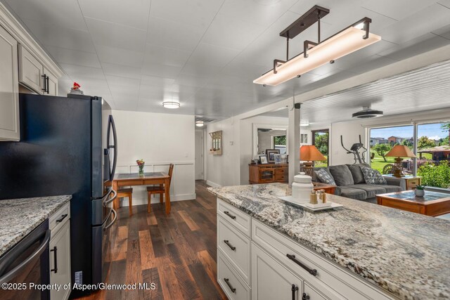 kitchen with light stone counters, dark wood finished floors, freestanding refrigerator, white cabinets, and dishwasher