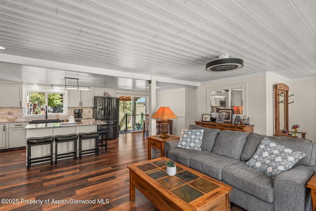 living area featuring plenty of natural light, dark wood finished floors, and crown molding