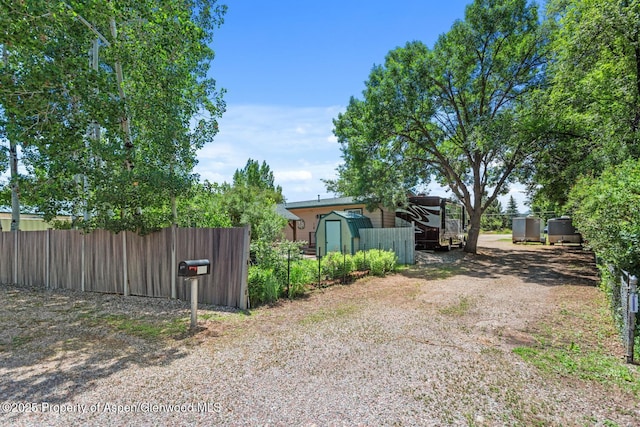 view of yard featuring an outbuilding, a shed, and fence