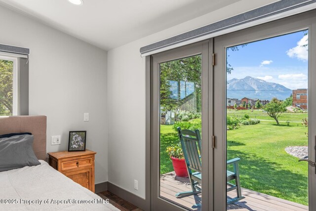 bedroom with dark wood-type flooring, access to outside, baseboards, and a mountain view