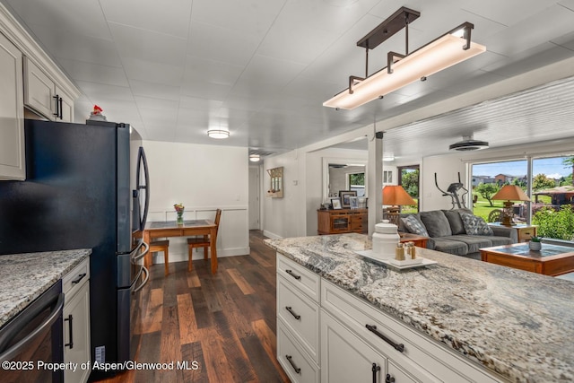 kitchen with light stone countertops, dishwasher, freestanding refrigerator, white cabinetry, and dark wood-style flooring