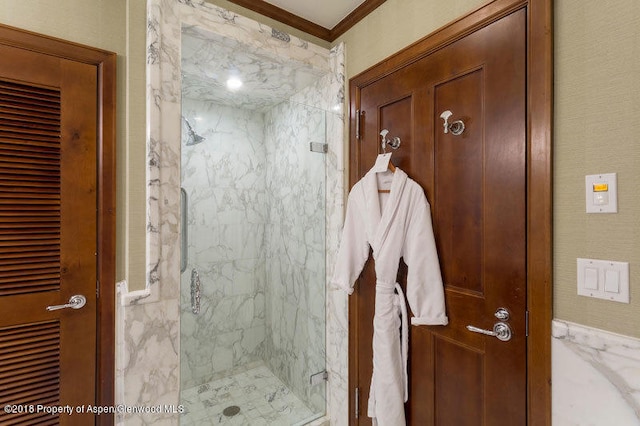 bathroom with a shower with shower door and ornamental molding