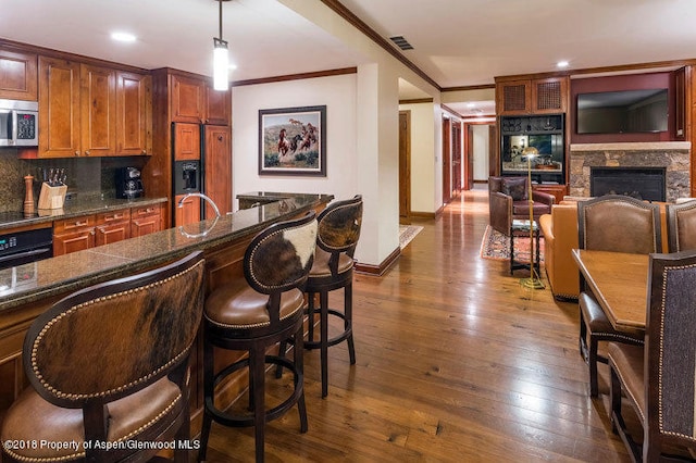 kitchen with black appliances, decorative backsplash, ornamental molding, decorative light fixtures, and dark hardwood / wood-style flooring