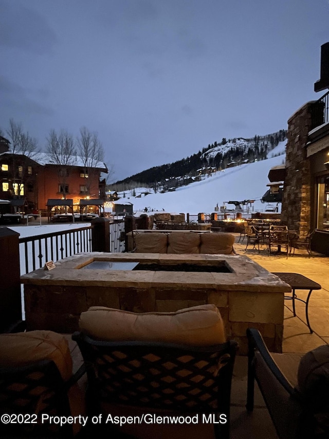 snow covered patio featuring a mountain view and an outdoor fire pit