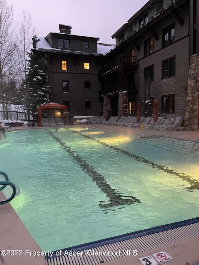 pool at dusk featuring a gazebo