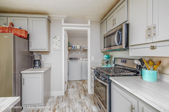 10155 6400th Rd, Montrose, CO 81401 - kitchen with washing machine and dryer, stainless steel appliances, light countertops, ornamental molding, and light wood finished floors