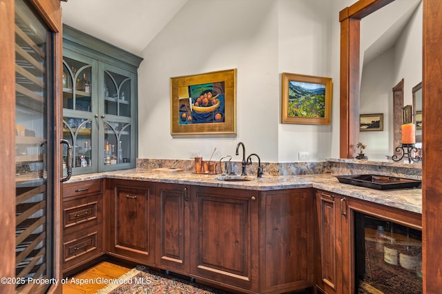 bar with wood finished floors, beverage cooler, wet bar, lofted ceiling, and a sink