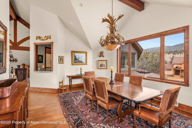 dining room with light wood-type flooring, baseboards, high vaulted ceiling, and beamed ceiling