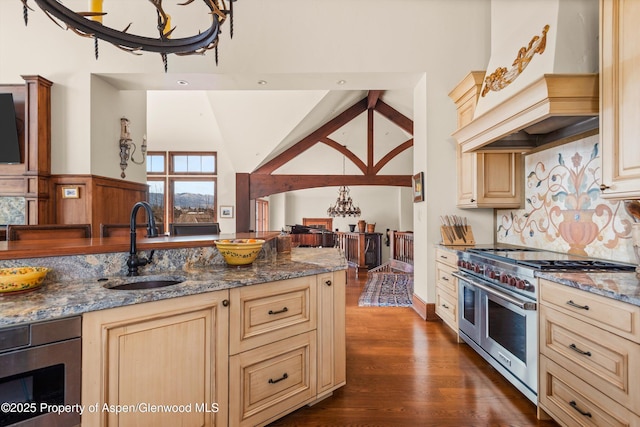 kitchen with custom exhaust hood, double oven range, cream cabinets, and a sink