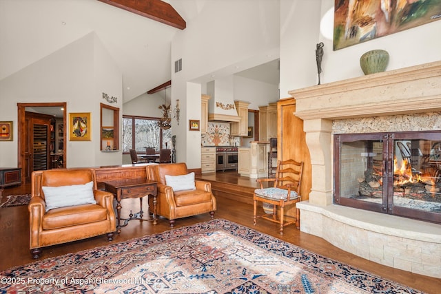 living room with visible vents, beam ceiling, a fireplace, wood finished floors, and high vaulted ceiling