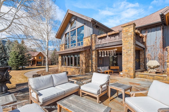 rear view of property with a balcony, board and batten siding, outdoor lounge area, and a patio